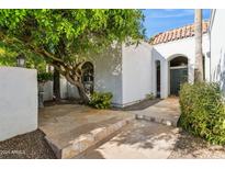 White stucco house with a tiled roof, featuring a stone walkway and lush landscaping at 8008 E Del Rubi Dr, Scottsdale, AZ 85258