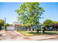 Charming single-story home with a brick exterior, solar panels, lush lawn, mature tree, and inviting front porch at 2157 W Mulberry Dr, Phoenix, AZ 85015