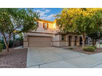 Two-story house with tan exterior, landscaped yard, and two-car garage at 1174 E Canyon Creek Dr, Gilbert, AZ 85295