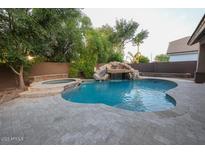 Inviting backyard oasis featuring a sparkling pool, spa, and waterfall feature at 2740 S Honeysuckle Ln, Gilbert, AZ 85295