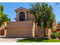 Two-story house with tan exterior, attached garage, and landscaped lawn at 6439 E Redmont Dr, Mesa, AZ 85215