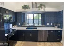 Modern kitchen with dark cabinetry, quartz countertops, and stylish backsplash at 7904 E Pepper Tree Ln, Scottsdale, AZ 85250