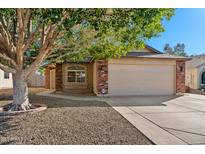 Charming single-story home with a two-car garage, brick accents and mature tree at 8549 E Carol Ave, Mesa, AZ 85208