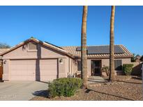 Single-story home with solar panels, two-car garage, and desert landscaping at 9621 N 94Th Dr, Peoria, AZ 85345