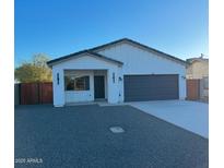 New construction home with modern exterior, two-car garage, and wood gate at 205 E Jackson Ave, Buckeye, AZ 85326