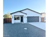 Newly constructed home with gray garage doors and wood gate at 205 E Jackson Ave, Buckeye, AZ 85326