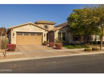 Tan two-story house with a three-car garage and nicely landscaped front yard at 10556 E Relativity Ave, Mesa, AZ 85212