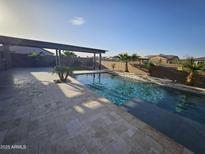 Backyard pool with beautiful stone pavers and a pergola covered seating area at 18404 W Long Lake Rd, Goodyear, AZ 85338