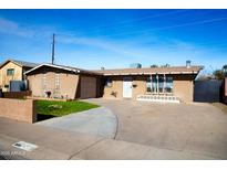 Ranch style home with a large driveway and well-maintained lawn at 4320 W Keim Dr, Glendale, AZ 85301