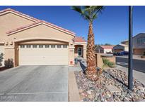 Tan house with a two-car garage and a palm tree in the front yard at 7008 W Cesar St, Peoria, AZ 85345