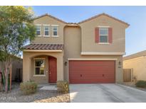 Two-story house with red garage door and landscaping at 40561 W Hillman Dr, Maricopa, AZ 85138