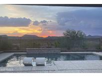 View of pool and sunset over desert landscape at 44512 N Sonoran Arroyo Ln, New River, AZ 85087