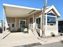 Tan mobile home with covered patio, landscaping, and a paved driveway at 840 S Aquamarine Dr, Apache Junction, AZ 85119