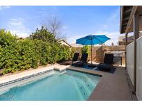 Inviting backyard oasis featuring a sparkling pool, lounge chairs, and a patio umbrella at 1328 E Binner Dr, Chandler, AZ 85225