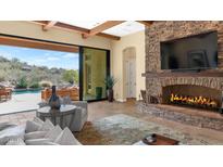 Bright living room with a stone fireplace and view of the backyard oasis at 7575 E Camino Salida Del Sol --, Scottsdale, AZ 85266