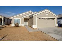 Beige house with a two-car garage and landscaped yard at 12750 W Dreyfus Dr, El Mirage, AZ 85335