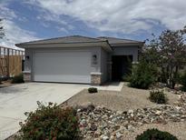 Charming single-story home featuring a two-car garage and desert landscaping with a stone facade and covered entrance at 17066 W Seldon Ln, Waddell, AZ 85355