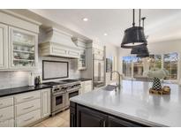 Gourmet kitchen boasts expansive island, stainless steel appliances, and white cabinetry at 7040 N 1St Ave, Phoenix, AZ 85021