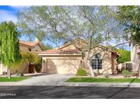 Tan house with tile roof, attached garage, and mature landscaping at 6458 E Raftriver St, Mesa, AZ 85215