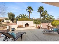 Desert landscaped backyard patio with fireplace, chaise lounges, and water feature at 12808 W Nogales Dr, Sun City West, AZ 85375