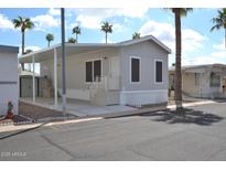 Well-maintained mobile home with a covered carport and desert landscaping under a sunny sky at 7807 E Main St # F36, Mesa, AZ 85207