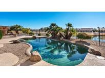 Inviting kidney-shaped pool with waterfall feature, surrounded by desert landscaping at 24623 S Lakeway Se Cir, Sun Lakes, AZ 85248