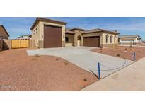 New home exterior featuring a three-car garage and desert landscaping at 17330 W Royal Palm Rd, Waddell, AZ 85355