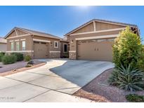 Tan two-story house with a three-car garage and desert landscaping at 19651 W Monterey Way, Buckeye, AZ 85396