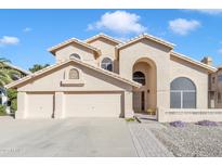 Inviting Southwestern home with an arched entryway, three-car garage, and well-maintained landscaping at 4968 E Grandview Rd, Scottsdale, AZ 85254