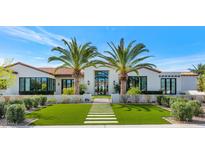 Stunning white home with a striking modern design, palm trees, and a lush green lawn at 5353 E Sanna St, Paradise Valley, AZ 85253
