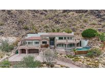 A sprawling multi-story home featuring a private pool and a stone exterior nestled in a mountainside landscape at 7929 N 55Th St, Paradise Valley, AZ 85253