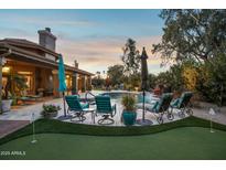 Stunning backyard oasis with a pool, putting green, and seating area at 10190 E Sunnyside Dr, Scottsdale, AZ 85260