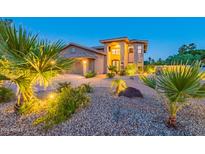 Two-story home featuring a circular driveway, a manicured lawn, desert landscaping and warm exterior lighting at 12015 S Tuzigoot Dr, Phoenix, AZ 85044