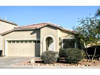 Tan house with a two-car garage and landscaping at 13915 N 132Nd Ln, Surprise, AZ 85379