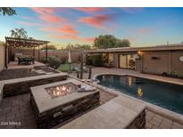 Expansive backyard oasis with a sparkling pool, fire pit, and built-in BBQ at 3229 E Mountain View Rd, Phoenix, AZ 85028