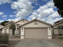 Tan two-car garage home with landscaping and a spacious driveway at 1704 E Redfield Rd, Gilbert, AZ 85234