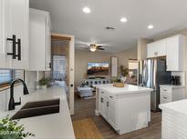 Modern kitchen with white cabinets, island, and stainless steel appliances at 3462 E Riopelle Ave, Gilbert, AZ 85298
