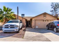 Tan house with a two-car garage and a landscaped yard at 8717 W Wilshire Dr, Phoenix, AZ 85037
