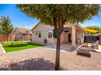 Landscaped backyard with a patio, fire pit, and trampoline at 16940 W Tonbridge St, Surprise, AZ 85374