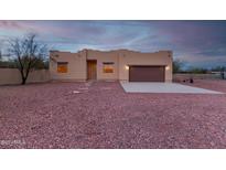 Tan stucco house with brown garage door, stone pathway, and gravel yard at 38913 N 21St Ave, Phoenix, AZ 85086