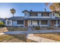 Two-story townhome with brick and blue siding, featuring a walkway and landscaping at 10101 N 91St Ave # 81, Peoria, AZ 85345