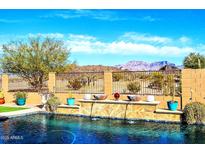 Inviting pool with a water feature and mountain views; landscaping and privacy fence enhance the backyard oasis at 17844 E Pacana Ct, Gold Canyon, AZ 85118