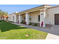 Charming single-story home with a brick facade, covered porch, and well-maintained landscaping at 9031 N 83Rd Way, Scottsdale, AZ 85258