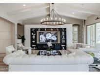 Elegant living room featuring white sofas, a large TV, and a stunning chandelier at 2351 E Cherrywood Pl, Chandler, AZ 85249