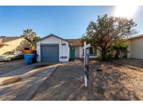 Cute one-story home with a gray garage door and turquoise front door at 3009 W Potter Dr, Phoenix, AZ 85027