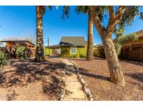 Adorable bungalow with a stone path leading to the entrance, surrounded by palm trees at 59 N Adams St, Wickenburg, AZ 85390