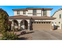 Two-story home with a tan facade, arched entryway, and a two-car garage at 904 E Zesta Ln, Gilbert, AZ 85297