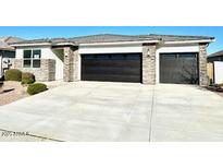 Modern two-story house with stone accents and a three-car garage at 18352 W Chama Dr, Wittmann, AZ 85361