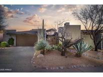 Desert landscape surrounds this contemporary home with a large garage and inviting entryway at 39565 N 107Th Way, Scottsdale, AZ 85262