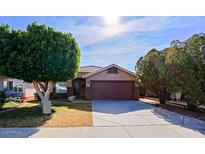 Single-story home with a brown garage door and landscaped front yard at 8605 W Paradise Dr, Peoria, AZ 85345